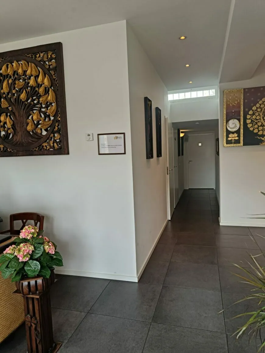 Gang met een houtsnijwerk van een boom met gouden bladeren aan de muur.